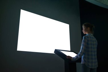 Woman looking at white empty large wall display - mockup image