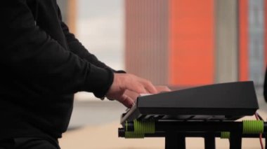 Man hands playing synthesizer on stage of open air concert - close up