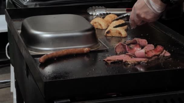 Preparing burger buns, bacon slices and long sausages on grill: slow motion — Wideo stockowe