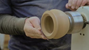 Slow motion: man using sandpaper for sanding piece of wood on lathe - close up