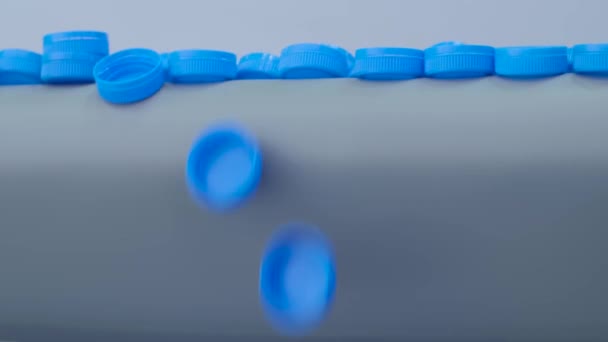 Produktionslinie - viele blaue Plastikflaschenverschlüsse fallen vom Förderband — Stockvideo