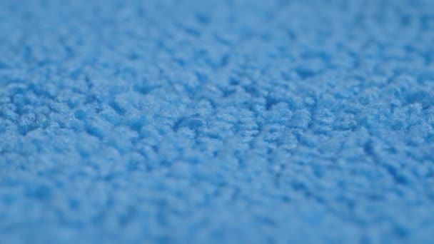Синяя ткань для очистки микроволокна на вращающейся поверхности - крупный план, селективная фокусировка — стоковое видео