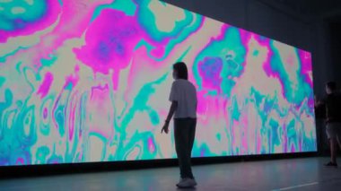 Çağdaş sanat: geniş AR ekranının önünde ayna efektiyle hareket eden insanlar