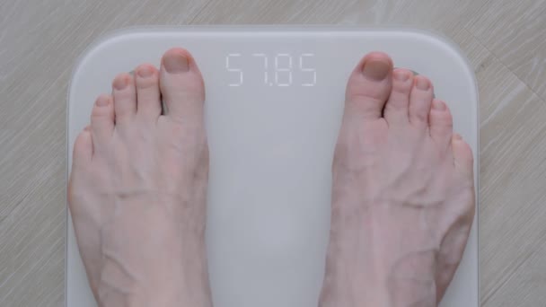 Мужчина босыми ногами наступает на цифровые весы пола - мужчина взвешивает себя: вид сверху — стоковое видео
