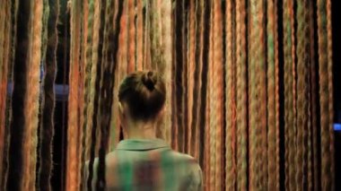 Asılı iplerin arasında renkli bir ışıkla yürüyen bir kadın.