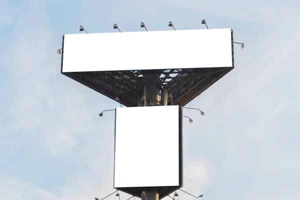 Two blank white billboards against blue sky