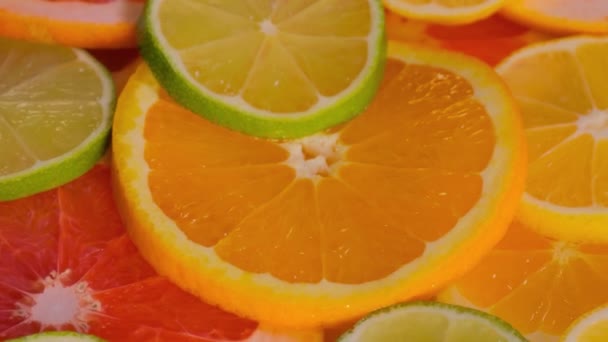 Rebanadas de cítricos: naranja, pomelo, limón y lima en la superficie giratoria — Vídeo de stock