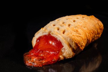 Elektrikli fırında çilek reçelli bir çörek: siyah arkaplan, yakın plan