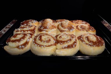 Elektrikli fırında on iki tarçınlı çörek pişiyor ve yükseliyor.