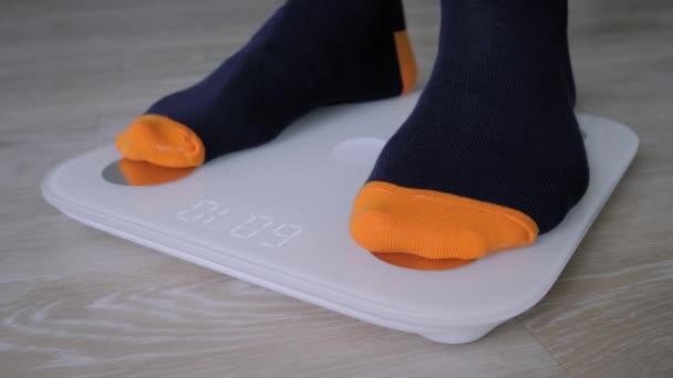 Közelkép: férfi lábak zokniban lépdelés a padlón mérlegek - férfi súlya magát — Stock videók