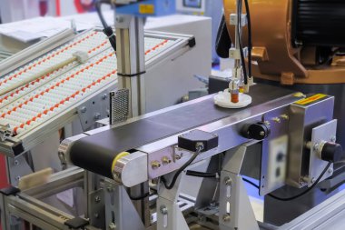 Taşıyıcı bant üzerinde plastik detayı hareket ettiren robotik kol manipülatörü seçin ve yerleştirin