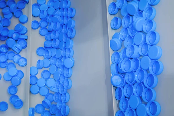 Many blue plastic bottle caps moving on conveyor belt - production line