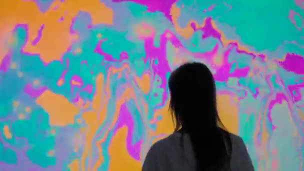 Vista trasera: mujer que se mueve delante de una gran pantalla AR con efecto espejo — Vídeos de Stock