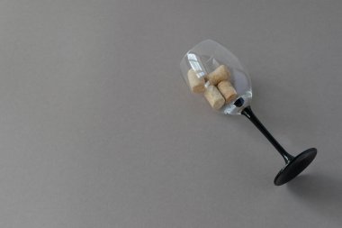 Şarap kadehinin en üst görüntüsünde gri arka planda şarap mantarları ve mesaj yeri var. Fotoğraf yatay..