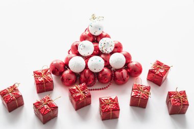 Kutlama kartpostalı. Beyaz arka planda, bir melek ve hediyelerle birlikte beyaz ve kırmızı toplardan yapılmış bir Noel ağacı. Yatay fotoğraf.