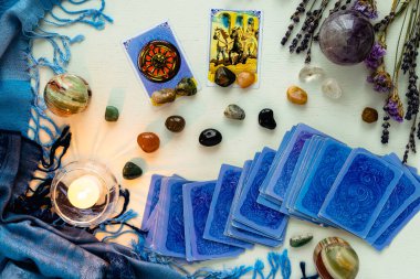 Minsk, Belarus - Şubat 2022: Servet ve at arabası kartları tarot kehanetinde mumlar ve taşlar ile birlikte kurumuş çiçekler ve mavi bir masa örtüsü ile birlikte. Büyü ve okült