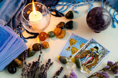 Minsk, Belarus - Şubat 2022: Tarot kehanetinde yer alan kadehlerin ve sevgililerin kartları. Kurumuş çiçekli ve mavi masa örtülü bir ışık masasında mumlar ve taşlar. Büyü ve okült