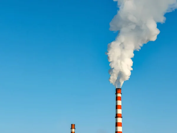危険な化学物質による大気汚染 青い空に対する植物の赤白パイプからの白い煙 横写真 — ストック写真