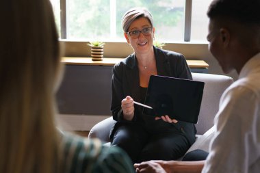 Olgun bir iş kadını iş arkadaşlarıyla toplantıda tartışıyor.