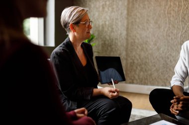 Olgun bir iş kadını iş arkadaşlarıyla toplantıda tartışıyor.