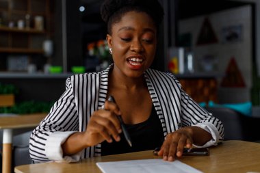 Cheerful african american young female professional laughing and looking away while working in modern corporate office