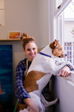 Kafkas kadın ressam portresi pencerenin kenarında köpeğiyle oturmuş kameraya bakıyor.