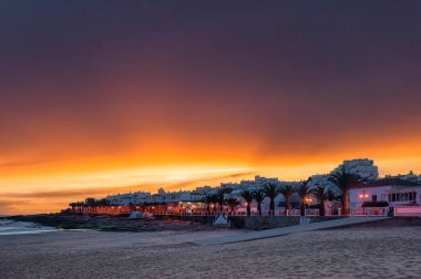 Sunset over the beach of Praia da Luz in the Algarve in Portugal. In the background the illuminated city
