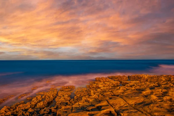 Sunset over the rocky coast in front of Praia da Luz in the Algarve in Portugal