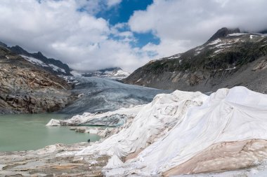 Valais 'teki Oberwald yakınlarında Rhone Buzulu ve Rhone Pınarı ile dağlar. Buzul erimesini önlemek için kısmen beyaz muşambayla kaplıdır.