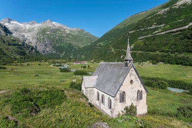 Rhone Buzulu 'nun önündeki Rhone Vadisi' nin manzarası ve İsviçre 'de Valais Oberwald yakınlarındaki Gletsch köyündeki Anglikan Şapeli.