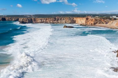Portekiz 'deki Algarve' de Sagres yakınlarında Cabo de Sao Vicente 'de kayalıkların önünde dalgalar var.