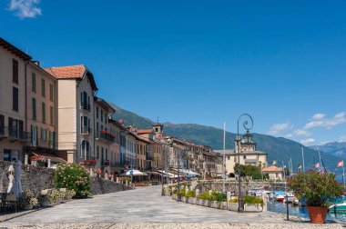 Waterfront promenade with historic house facades in Cannobio. In the background the Santuario della SS Pieta pilgrimage church. Cannobio is a town in Piedmont in northern Italy clipart
