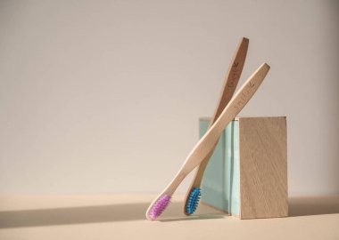 Açık bej arka planda bambu ahşaptan yapılmış iki çevre dostu antibakteriyel diş fırçasının yaratıcı bileşimi. Doğal organik öz bakım ürünleri.