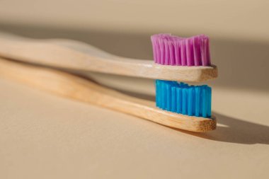 Açık bej arka planda bambu ağacından yapılmış iki çevre dostu antibakteriyel diş fırçası. Çevresel bakım eğilimleri.