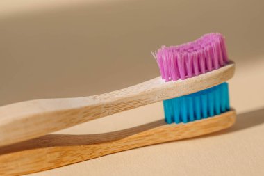 Açık bej arka planda bambu ağacından yapılmış iki çevre dostu antibakteriyel diş fırçası. Çevresel bakım eğilimleri.