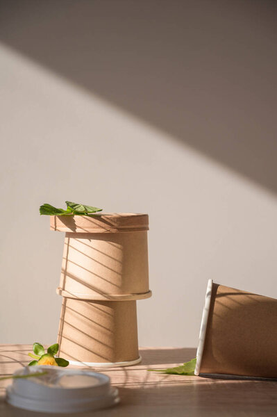 Одноразовые, компостируемые, перерабатываемые, биоразлагаемые, без пластика бамбуковые горшки с крышками на деревянном столе на белом фоне.