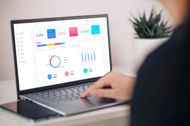 İş kadını dizüstü bilgisayardaki istatistikleri analiz ediyor, finansal grafiklerle çevrimiçi çalışıyor, veri analizi ve proje yönetimi konsepti için iş yazılımı kullanıyor, arka yakın görünüm