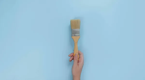 Малювати Пензлик Руці Ізольовано Синьому Фоні — стокове фото
