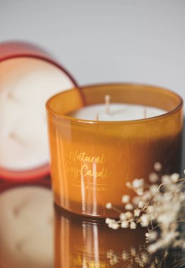 Cam kavanozdaki doğal mum ve ayna yüzeyindeki kurumuş çiçekler..