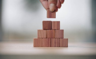 Tahta masa ile ahşap bloğu üst üste dizme el düzenlemesi. Büyüme süreci için iş konsepti