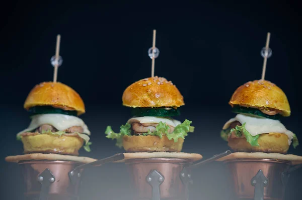 Small mini chicken cheese sliders grilled burgers with lettuce and cucumbers, served as appetizers for sharing