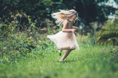Küçük bir kız ormanda dans ediyor.