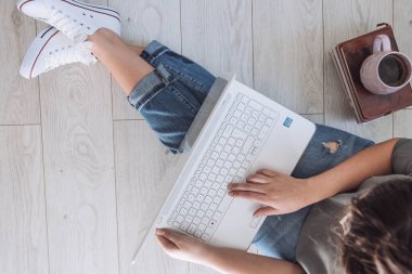 Genç öğrenci evde dizüstü bilgisayarıyla çalışıyor. Ev konsepti üzerinde çalışıyorum. İş yerinde yerde otururken dizüstü bilgisayarda çalışan kadın serbest çalışanın yukarıdan çekimleri. Üst görünüm