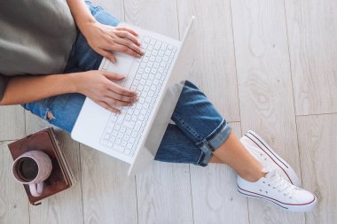 Genç öğrenci evde dizüstü bilgisayarıyla çalışıyor. Ev konsepti üzerinde çalışıyorum. İş yerinde yerde otururken dizüstü bilgisayarda çalışan kadın serbest çalışanın yukarıdan çekimleri. Üst görünüm