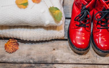 Havalı, sıcak yün kazak ve kırsal ahşap arka planda kırmızı ayakkabılar. Düz yerde, üst tarafta. Bayan giysi takımı.. 