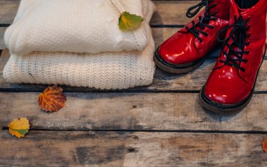 Havalı, sıcak yün kazak ve kırsal ahşap arka planda kırmızı ayakkabılar. Düz yerde, üst tarafta. Bayan giysi takımı.. 