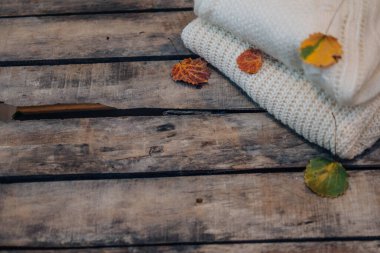 Sonbahar kompozisyonu. Beyaz kadınlar süveter giyer, sonbahar yaprakları eski moda ahşap arka planda. Düz konum, üst görünüm, kopyalama alanı