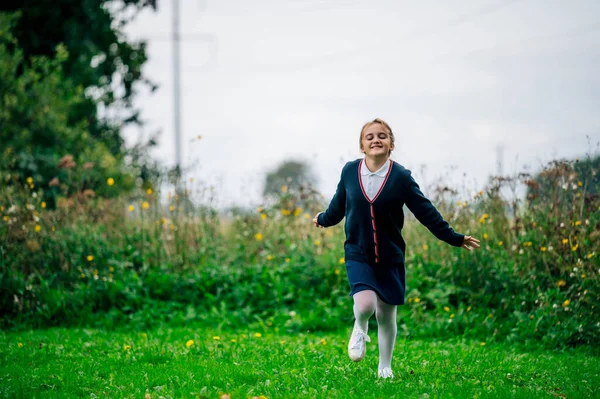 Okul üniformalı bir kız parkta koşuyor. Okul yılının başlangıcı konsepti. Okula geri dön.