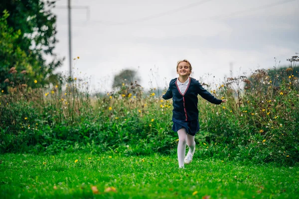 Okul üniformalı bir kız parkta koşuyor. Okul yılının başlangıcı konsepti. Okula geri dön.