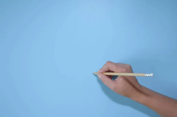 Vrouwelijke Hand Met Een Potlood Een Blauwe Achtergrond Bovenaanzicht Kopieer — Stockfoto